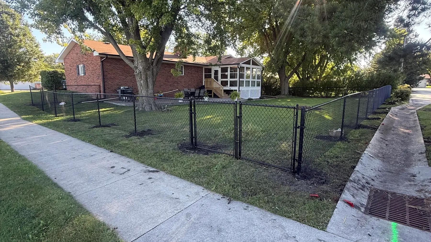Black chain link fence and gate enclosing a yard, built by Precision Fence Co. in the Fort Dodge area