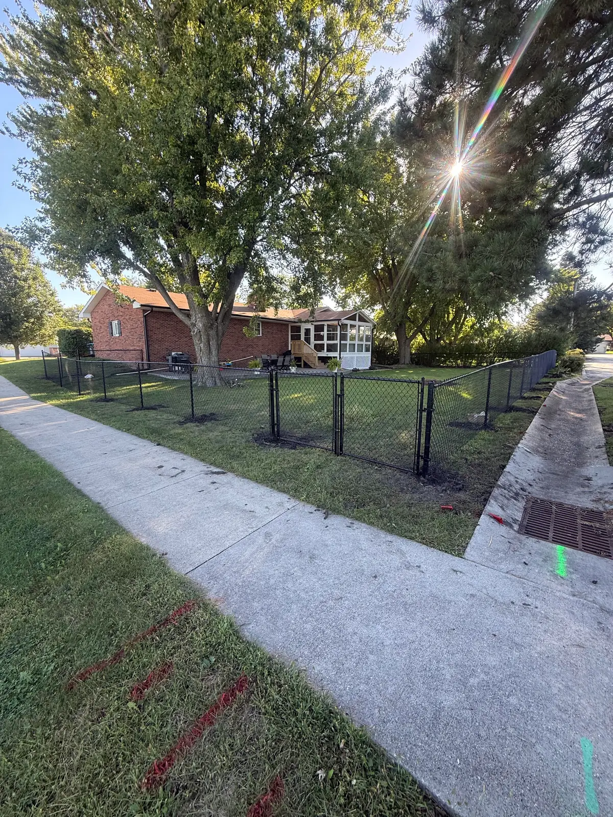 Black chain link fence along a sidewalk line, built by Precision Fence Co.