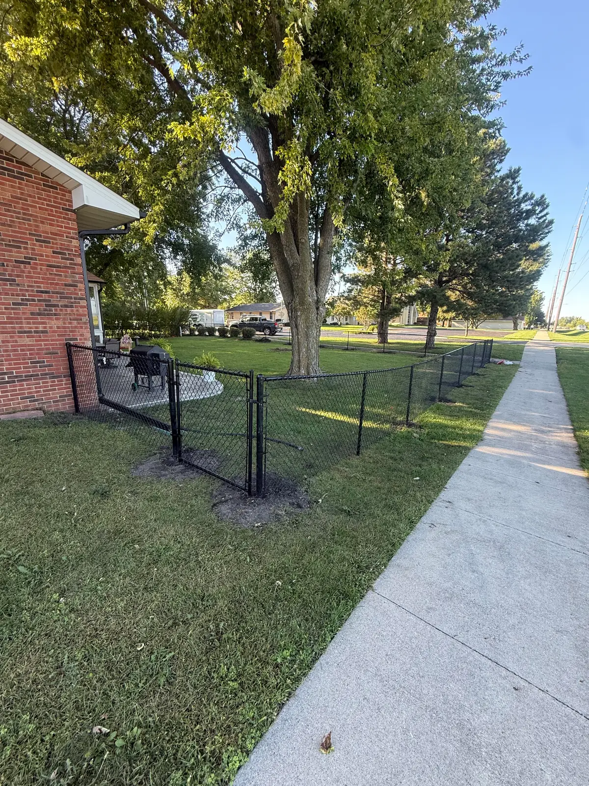 Black vinyl-coated chain link fence with a walk gate, built by Precision Fence Co.